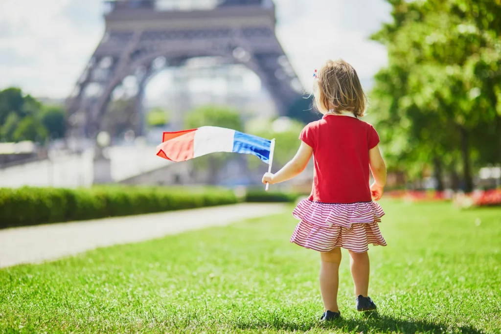 Little girl holding a French flag, taking part in the Bastille Day festivities in Paris.