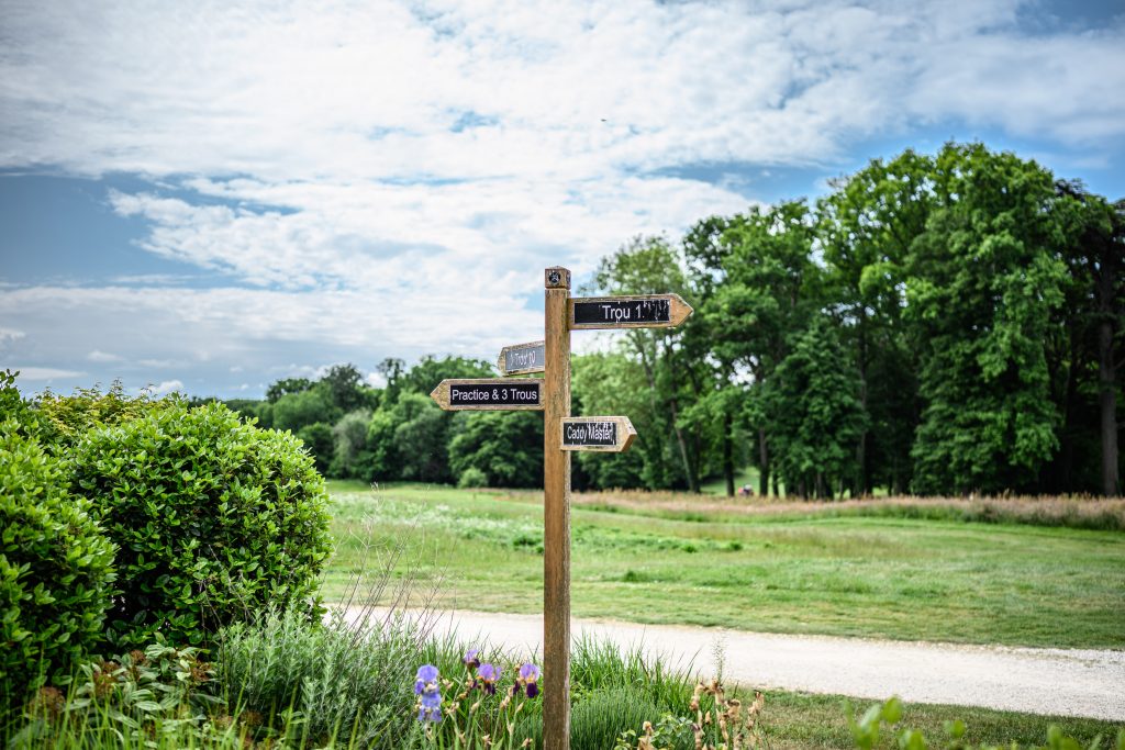 Wooden signpost with directions surrounded by lush greenery in Burgundy, France under a bright summer sky. The beauty of traveling green.