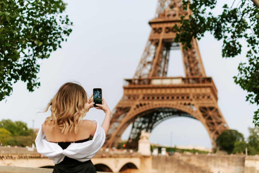 Woman taking a photo of the Eiffel Tower; Photographer's guide to Paris