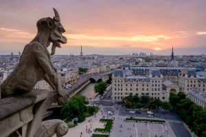 Gargoyle overlooking Paris and the Eiffel Tower at sunset from Notre-Dame Cathedral.