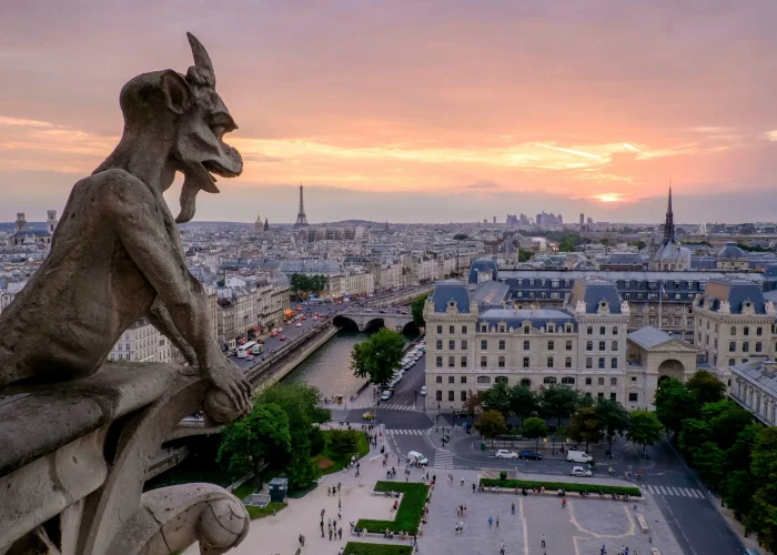Gargoyle overlooking Paris and the Eiffel Tower at sunset from Notre-Dame Cathedral.