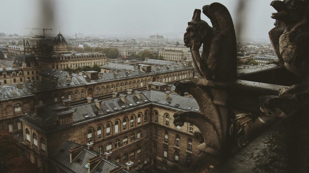 Spooky statue overlooking Paris from atop the Gothic Notre Dame. Halloween in Paris vibes.