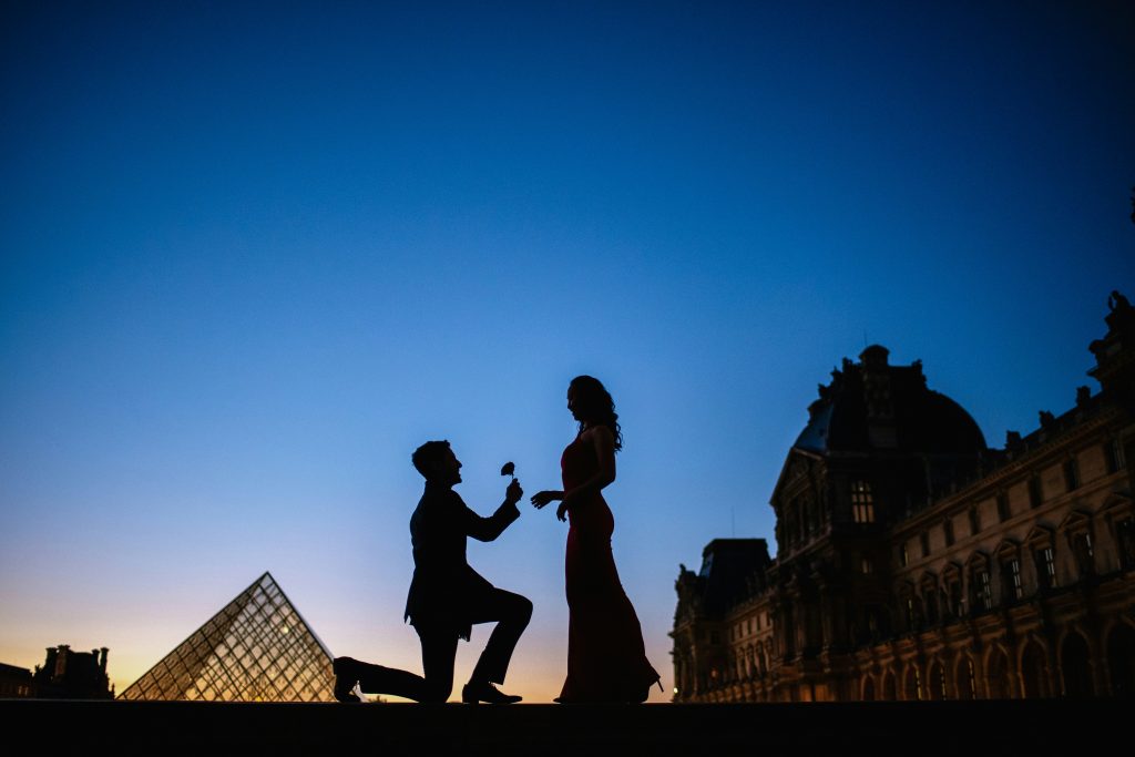 Romantic Paris proposal with a rose in front of the Louvre.