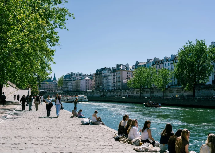 Parisians soaking in the sunshine on the Seine river banks during warm weather.