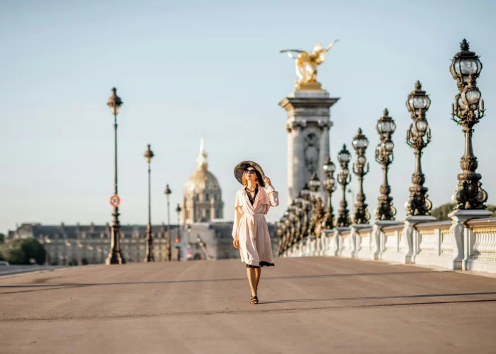 Woman with sunhat walking on a brigde in Paris.