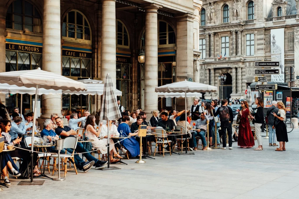 People enjoying a sunny day at the Le Nemours café terrace, near the Louvre Museum in Paris.