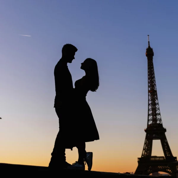 Silhouette of a couple hugging in front of the Eiffel Tower.