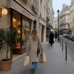 Woman carrying shopping bags on a Parisian street.