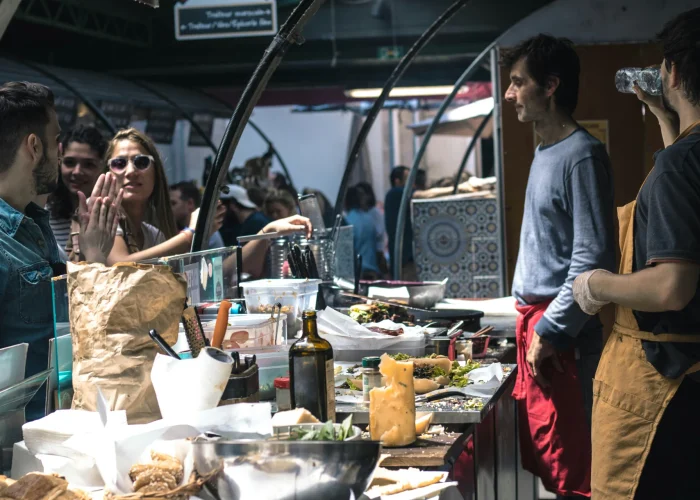 Food vendors serving customers at the Marché des Enfants Rouges, Paris.